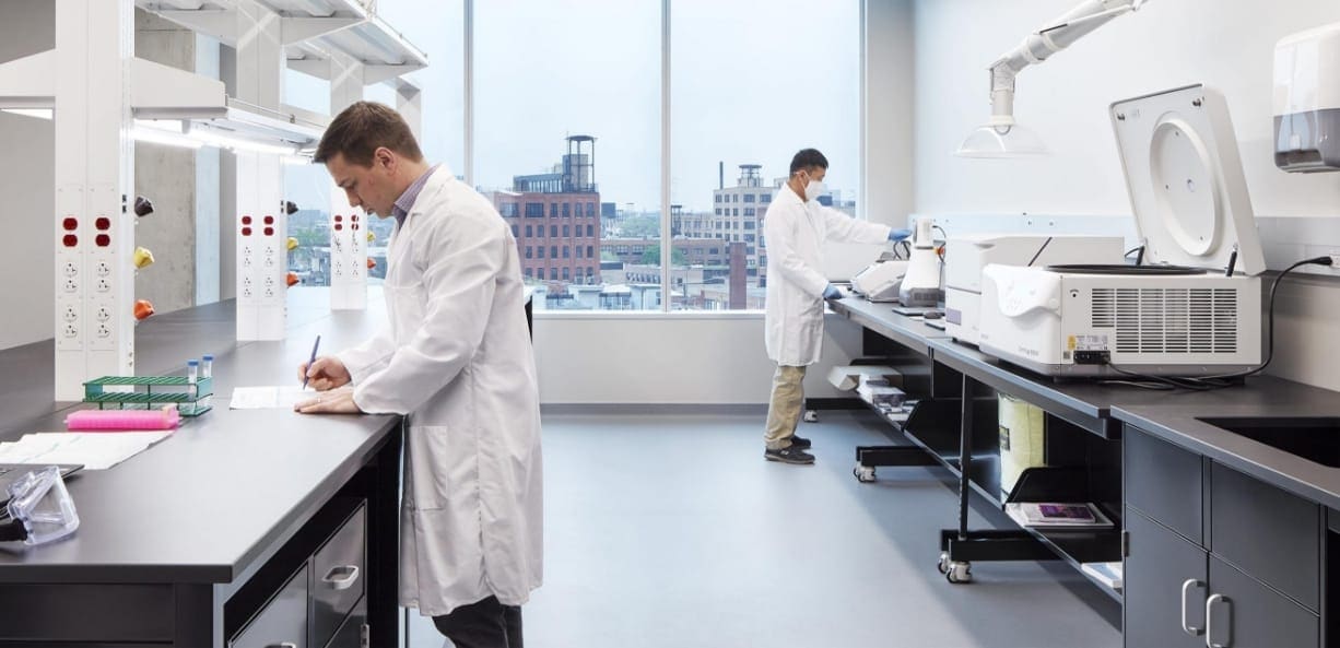 Two scientists conduct tests in a lab with city views